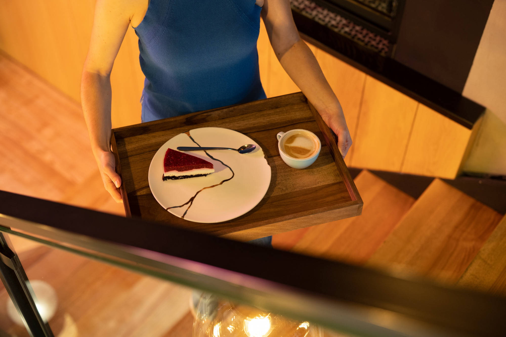 Woman carrying wooden walnut tray and kintsugi plate up the stairs