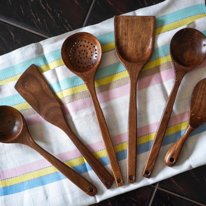 Küchenutensilien aus dunklem Nussbaumholz auf Küchenhandtuch