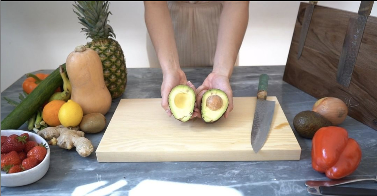 Woman holding cut avocado in hands